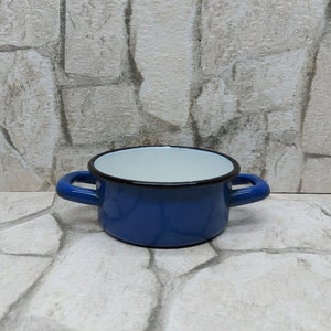 Peut inclure: Une petite casserole en émail bleu avec deux poignées. Le pot a un intérieur blanc et un bord noir. Ce pot de cuisson de style vintage convient à diverses utilisations en cuisine.