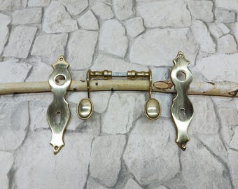 May include: A pair of antique brass door handles with keyholes and decorative details. The handles are attached to a wooden dowel.