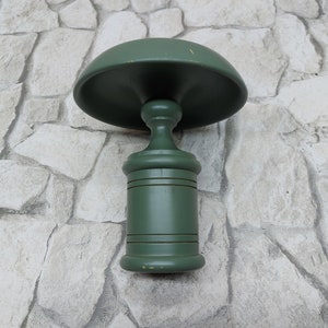 May include: A green wooden decorative object with a mushroom-shaped top and a cylindrical base. The object is painted in a solid green colour and has a classic, vintage design. The object is likely a decorative item or a small table.
