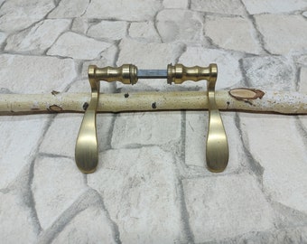 May include: A pair of gold door handles with a brushed finish. The handles are attached to a wooden dowel.