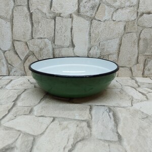 Puede incluir: Un cuenco de esmalte verde con interior blanco y borde negro. El cuenco es redondo y poco profundo. Probablemente se utiliza para servir o preparar alimentos. El diámetro del cuenco es de unos 25 cm.