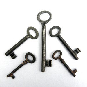 May include: Five antique keys with tarnished metal finishes arranged in a starburst pattern on a white background.