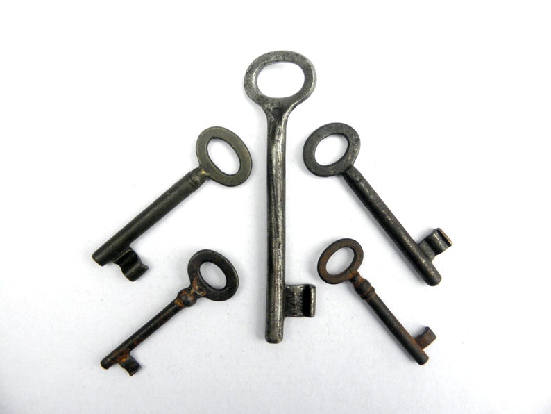 May include: Five antique keys with tarnished metal finishes arranged in a starburst pattern on a white background.