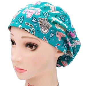 Op de afbeelding: Turquoise scrub cap met een herhalend patroon van roze en witte anatomische illustraties, harten en de tekst "you see area". De cap wordt getoond op een mannequinhoofd.