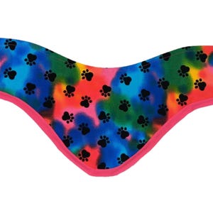 May include: A colourful tie-dye dog bandana with a pink trim and black paw prints.
