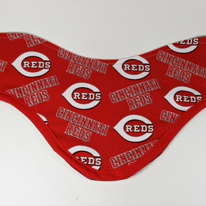May include: Red fabric bib with a white Cincinnati Reds logo pattern.