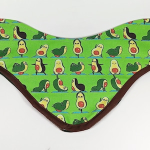 Può includere: Un bandana di stoffa verde con un bordo marrone presenta un motivo ripetuto di avocado dei cartoni animati che fanno pose di yoga.