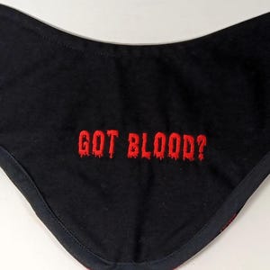 May include: Black fabric bib with red embroidered text that reads "GOT BLOOD?"