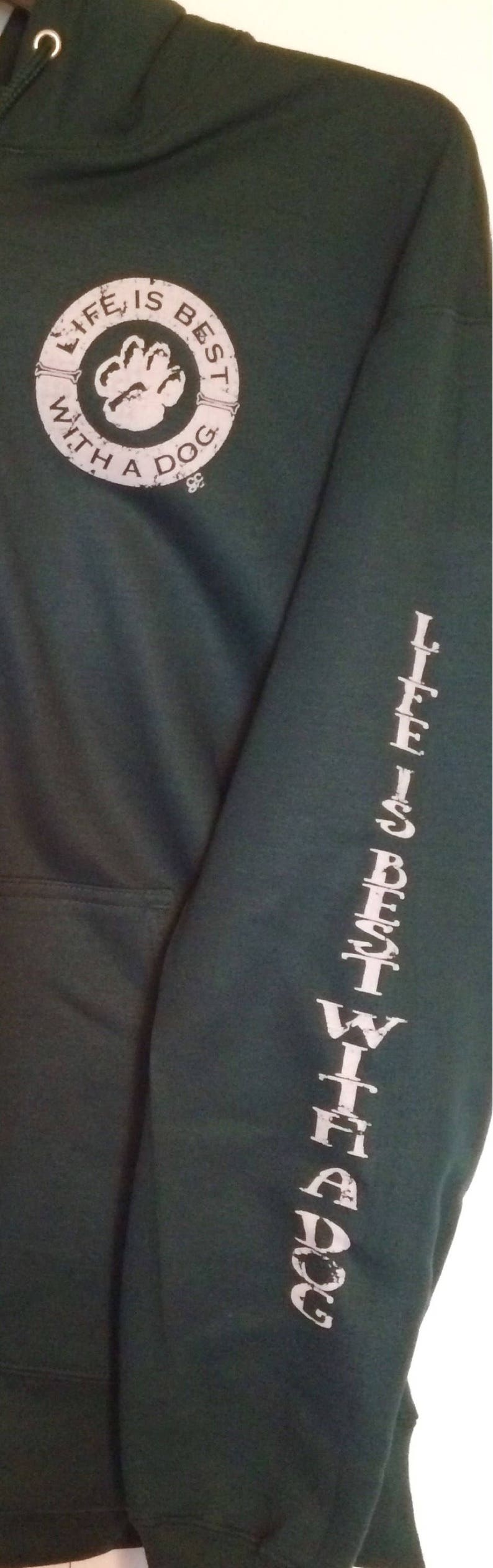 May include: Dark green hoodie with a white paw print graphic inside a circle that reads "LIFE IS BEST WITH A DOG." The sleeve has the text "LIFE IS BEST WITH A DOG" printed vertically in white.