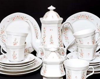 May include: A white porcelain tea set with a floral pattern. The set includes a teapot, sugar bowl, creamer, and four cups and saucers.