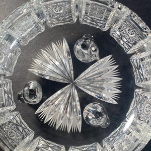 May include: A clear glass bowl with a cut glass design. The bowl has three feet and is ideal for serving fruit or snacks.
