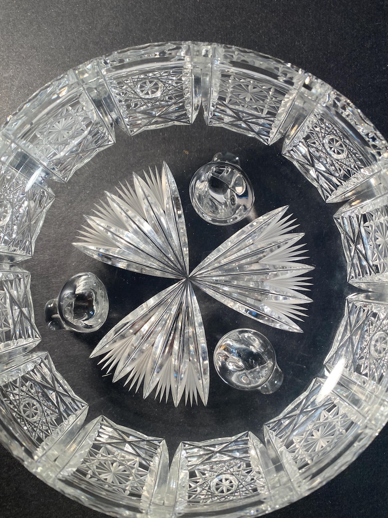 May include: A clear glass bowl with a cut glass design. The bowl has three feet and is ideal for serving fruit or snacks.