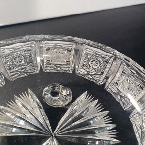 May include: A clear glass bowl with a cut glass design. The bowl has a scalloped edge and a starburst pattern in the centre.