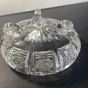 May include: A clear glass bowl with a cut glass design. The bowl has three feet and is ideal for serving snacks or desserts.