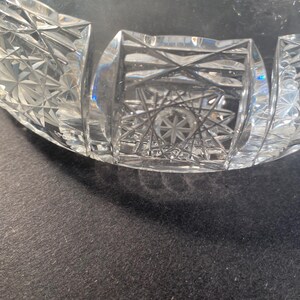 May include: A clear glass bowl with a cut glass design. The bowl has a starburst pattern in the centre and a geometric pattern around the rim.