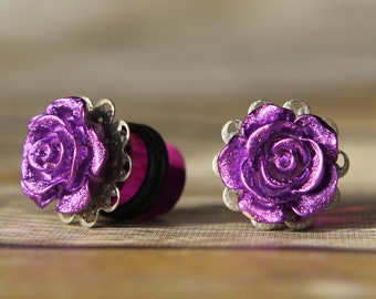 May include: A pair of purple rose ear gauges with silver accents. The gauges are made of metal and have a rose design.