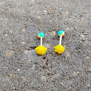 May include: Two yellow rose flower barbell tongue rings with turquoise and yellow accents.