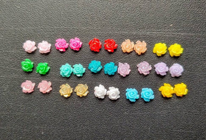 May include: Assortment of 20 colorful plastic rose flower embellishments. The roses are in various colors, including pink, red, blue, green, yellow, and white.