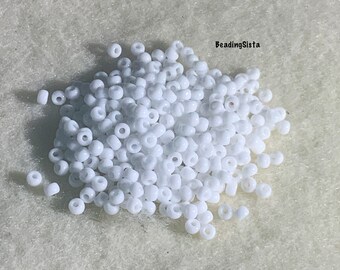 May include: A pile of small, white round seed beads.