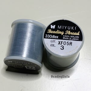 May include: Two spools of gray Miyuki Beading Thread, one with the label "Beading Thread 330dtex 100% Nylon Made in Japan LOT. XFO5R COL. 3" and the other with the label "Beading Thread 50m".