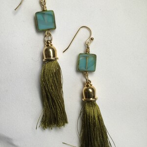 May include: A pair of green tassel earrings with a square turquoise glass bead on each earring.