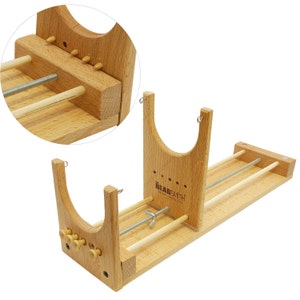 May include: Wooden beading loom with a stand and adjustable tension rods. The loom has a beaded design and the text "Beadsmith" is printed on the side.