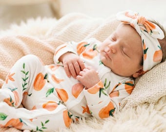Pijama para bebé con diseño de melocotón, gorro con nudo superior o diadema, de una pieza con pies y broches.