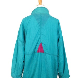 May include: A teal blue windbreaker jacket with a pink triangle on the back.
