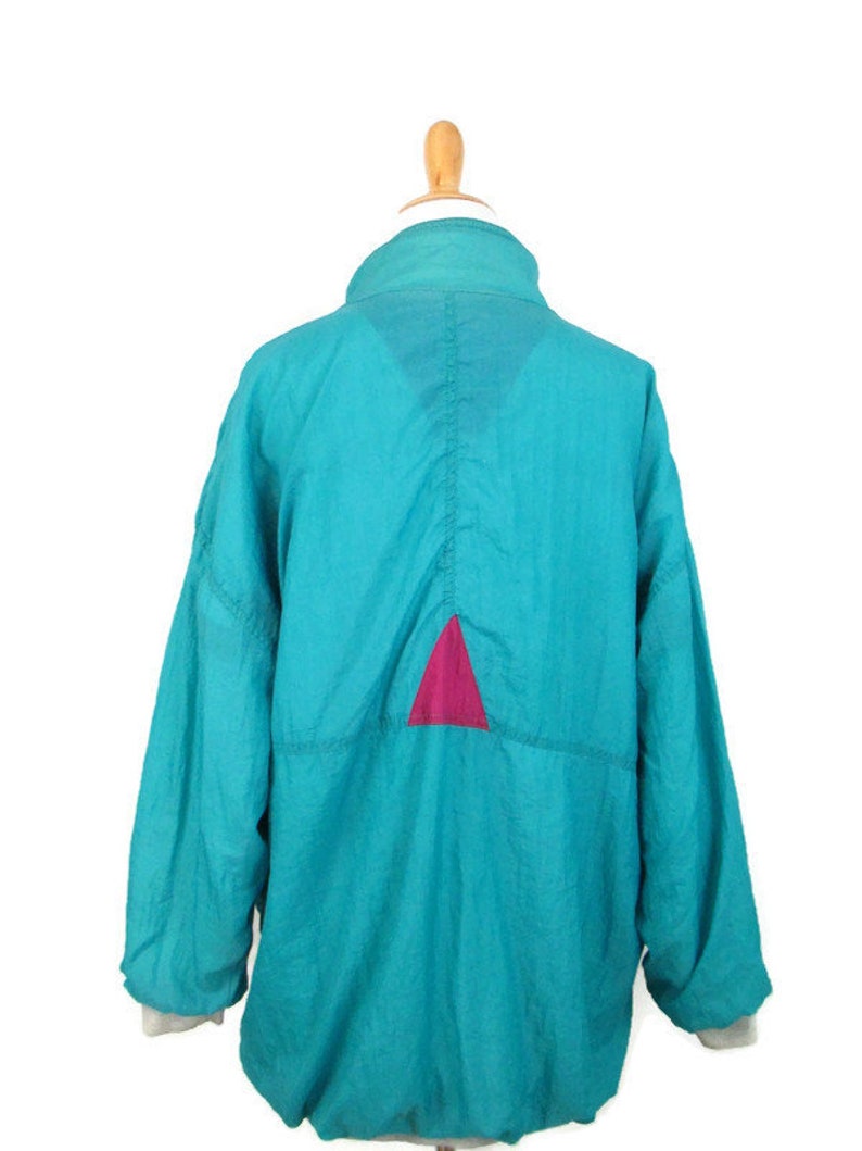 May include: A teal blue windbreaker jacket with a pink triangle on the back.