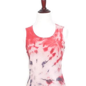 May include: A sleeveless tie-dye tank top in shades of red, pink, and white. The top has a scoop neck and a relaxed fit.