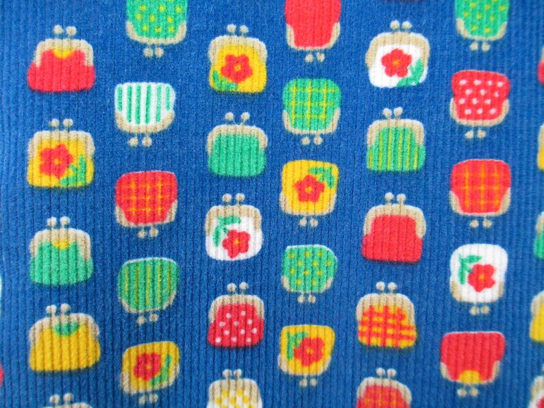 May include: A blue fabric with a repeating pattern of colorful purses. The purses are in various colors, including red, yellow, green, and white. The purses have different designs, including polka dots, stripes, and flowers.