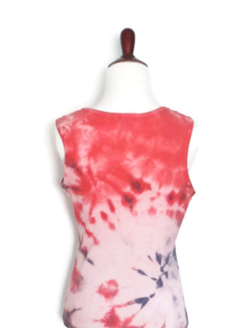 May include: Red, white and blue tie-dye sleeveless tank top. The tank top is a light pink colour with red and blue tie-dye swirls.
