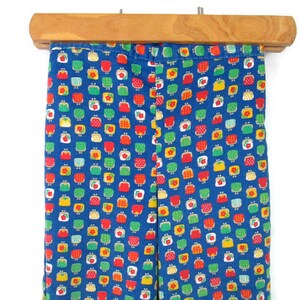 May include: Blue corduroy pants with a repeating pattern of small red, yellow, and green purses.