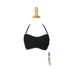 May include: Black halter top bikini top with a bandeau style. The top is made of a soft, stretchy fabric.
