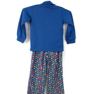 May include: A blue long-sleeved shirt with a collared neckline and matching blue pants with a colorful geometric pattern.