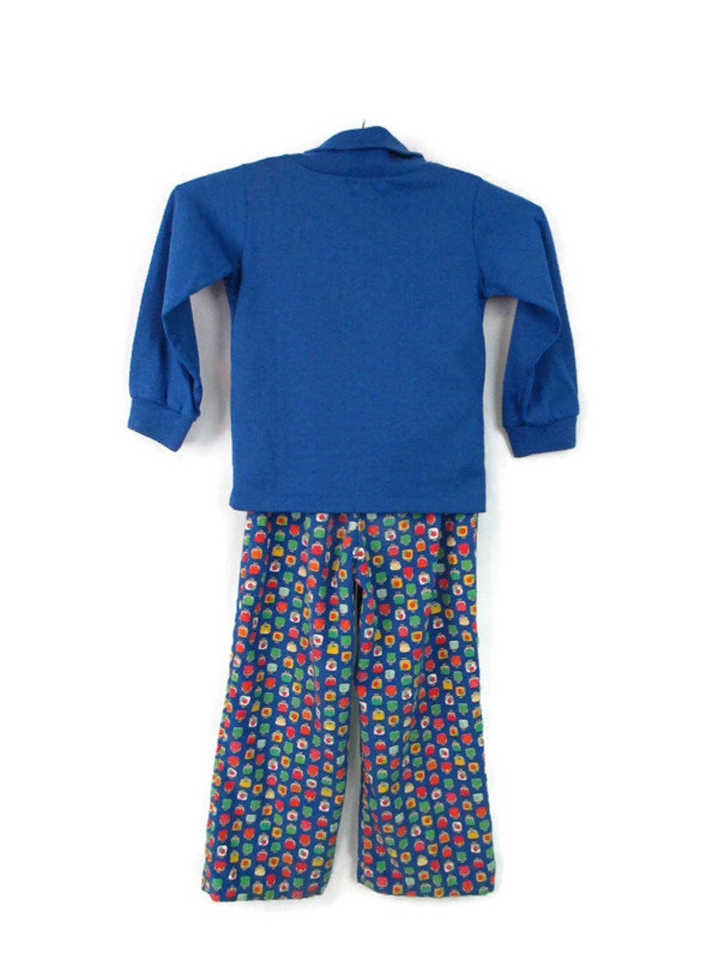 May include: A blue long-sleeved shirt with a collared neckline and matching blue pants with a colorful geometric pattern.