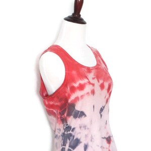 May include: A red and white tie-dye tank top with a scoop neck. The tank top is made of a soft, lightweight fabric and has a relaxed fit.