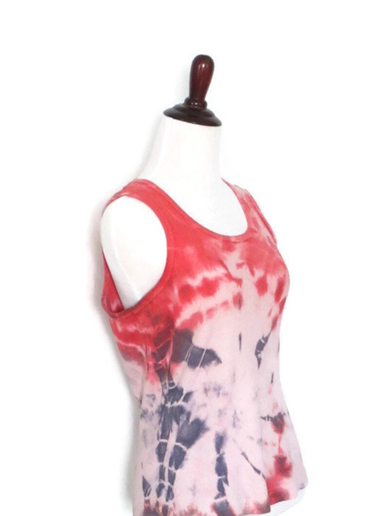 May include: A red and white tie-dye tank top with a scoop neck. The tank top is made of a soft, lightweight fabric and has a relaxed fit.