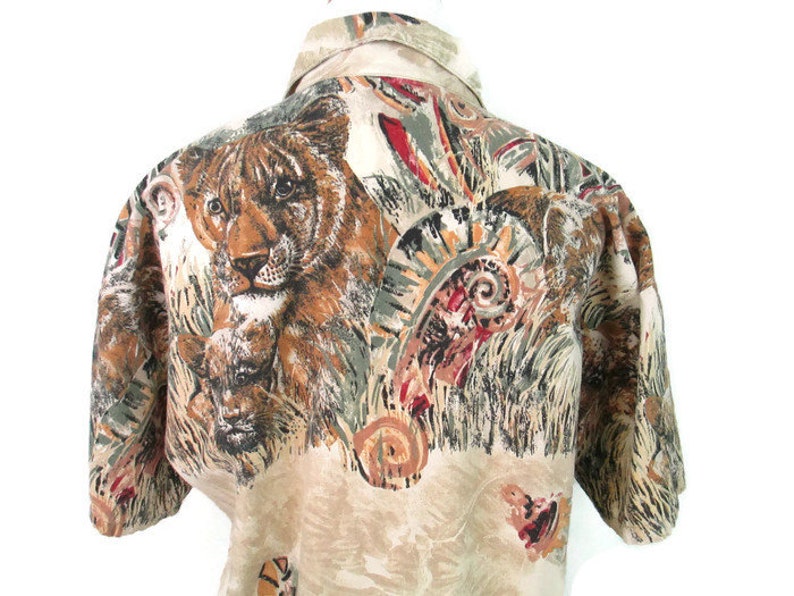 May include: A beige short-sleeved button-up shirt with a colorful print of tigers, leaves, and abstract patterns.