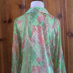 May include: A long-sleeved shirt with a green, pink, and white abstract feather pattern.