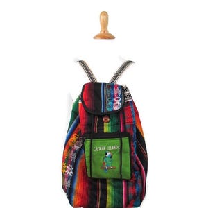 May include: A colourful woven backpack with a green pocket that says "Cayman Islands" and a parrot design. The backpack has a black, red, green, blue and yellow striped pattern.
