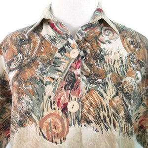 May include: A beige button-up shirt with a short sleeve and a print of brown and black animal faces on a beige background.