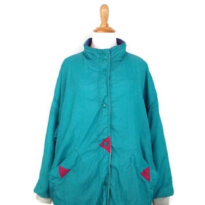 May include: A teal blue jacket with a snap closure and two pockets. The jacket has red and purple accents on the pockets and collar.