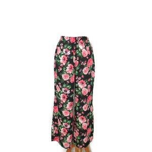 Puede incluir: Pantalón negro de pierna ancha con estampado floral de flores rosas y verdes.