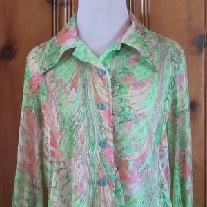 May include: A long-sleeved, green, pink, and white patterned shirt with a teal button-up closure.
