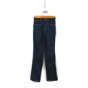 May include: A pair of dark blue denim jeans hanging on a wooden hanger. The jeans have a straight leg and a classic five-pocket style.