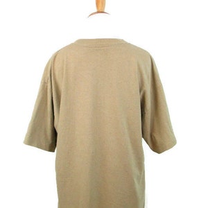 Puede incluir: Una camiseta lisa de color marr&oacute;n claro con mangas cortas.