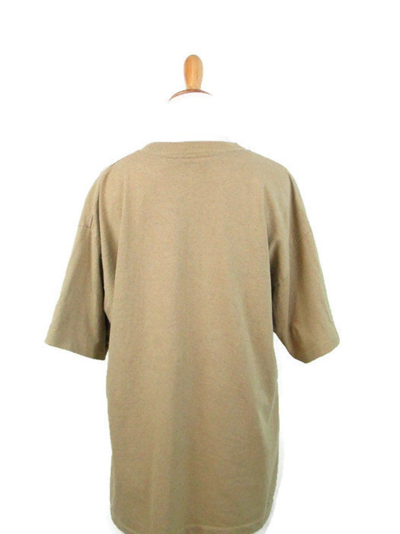 Puede incluir: Una camiseta lisa de color marr&oacute;n claro con mangas cortas.