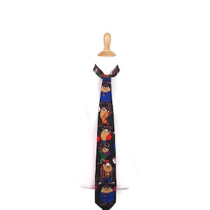 May include: A black tie with a colorful cartoon print of a Tasmanian devil. The tie features a blue, red, yellow, and orange color scheme.