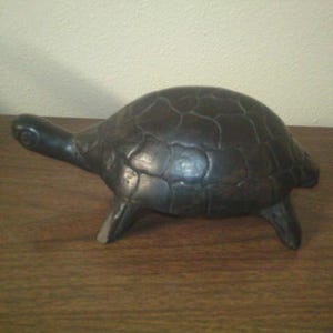 May include: A black turtle figurine with a detailed shell and four legs. The turtle is made of a smooth, hard material and has a realistic appearance.